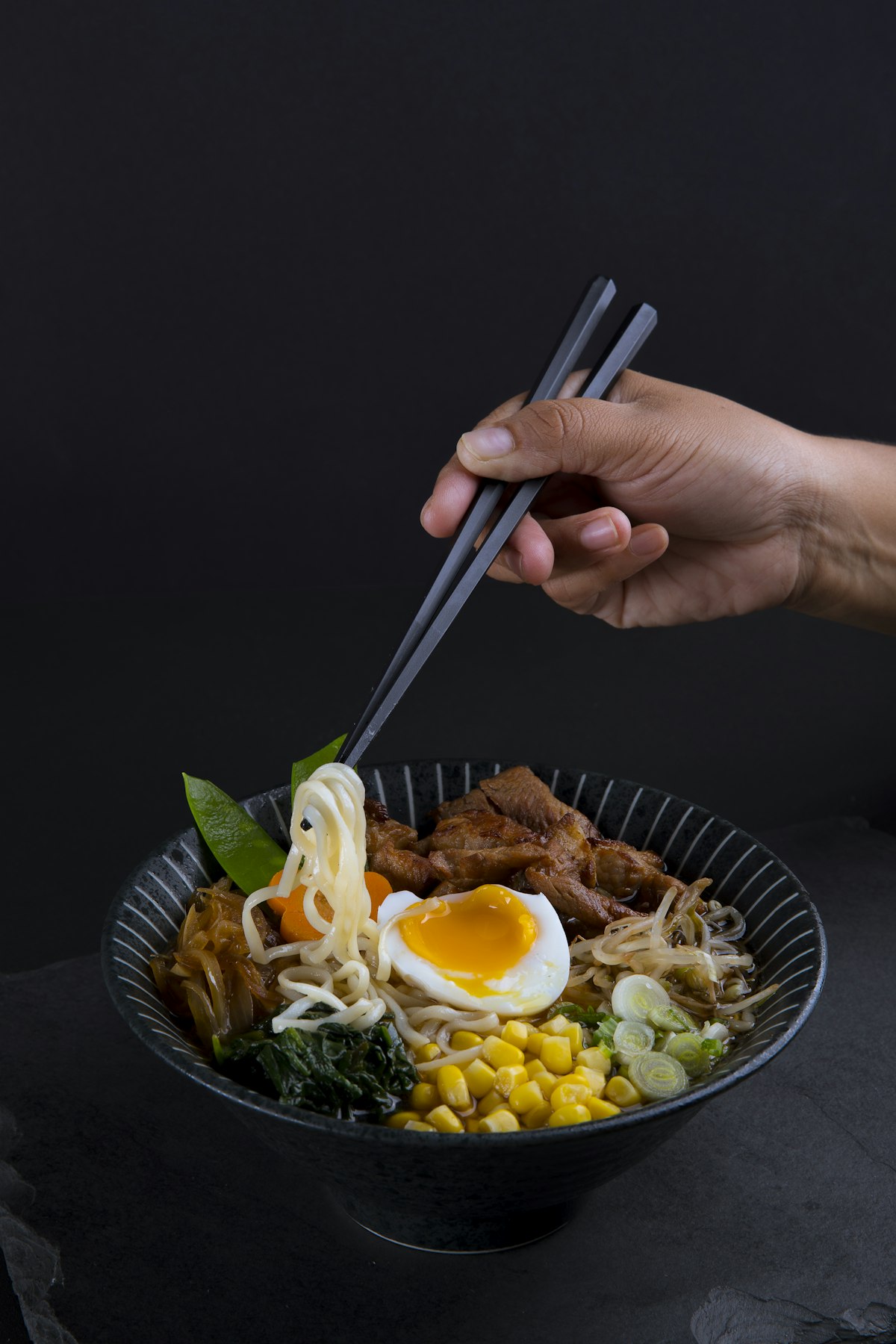 Cold sesame noodles in a bowl with vegetables and sesame seeds