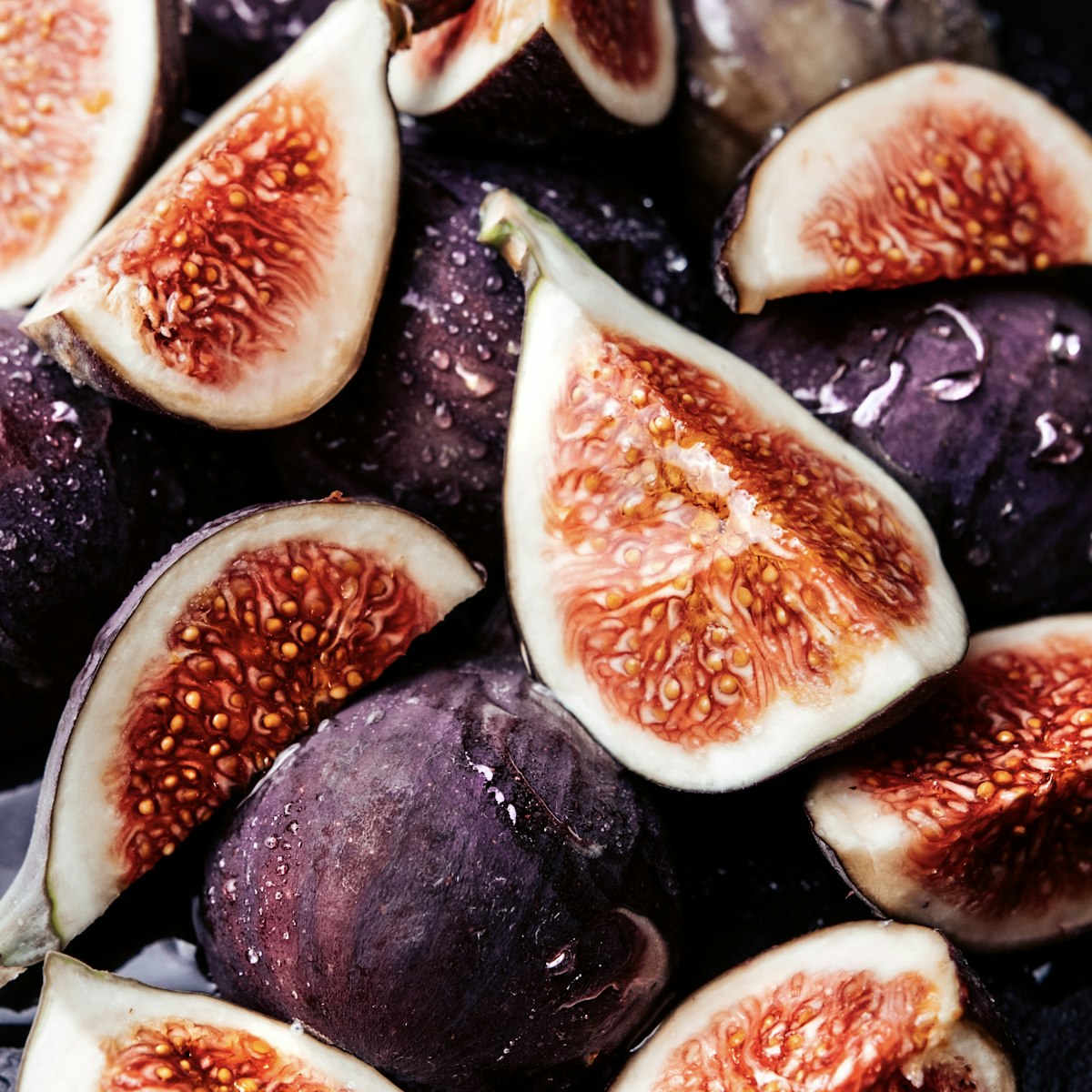 Fresh figs halved on a wooden board with honey and herbs