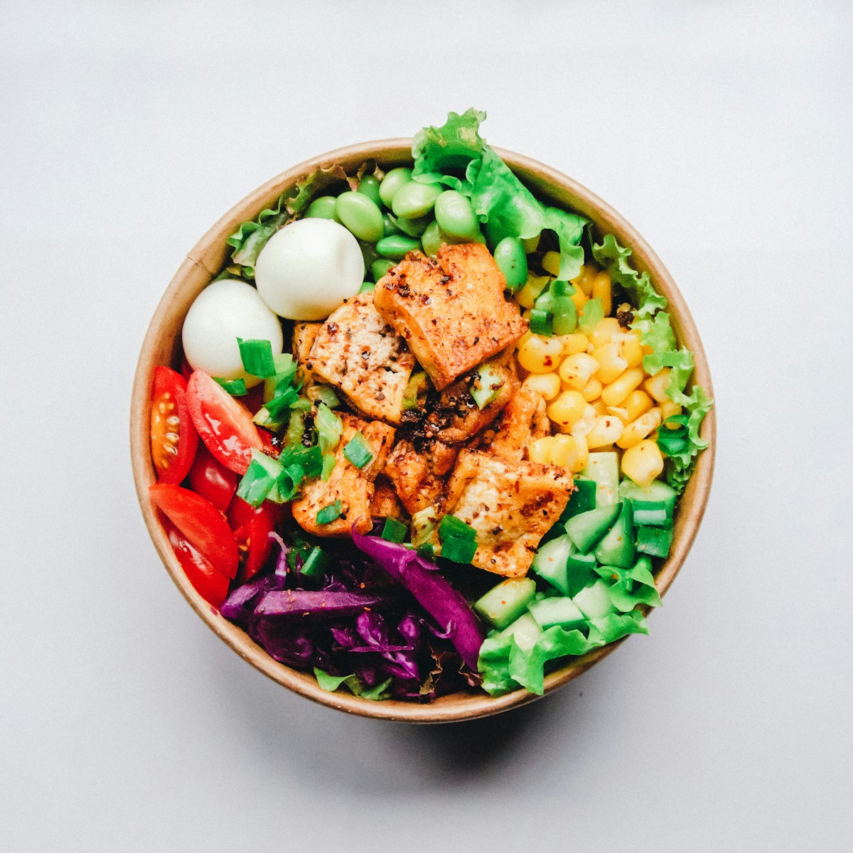 Hot honey glazed salmon fillet over white rice with cucumber and avocado in a bowl