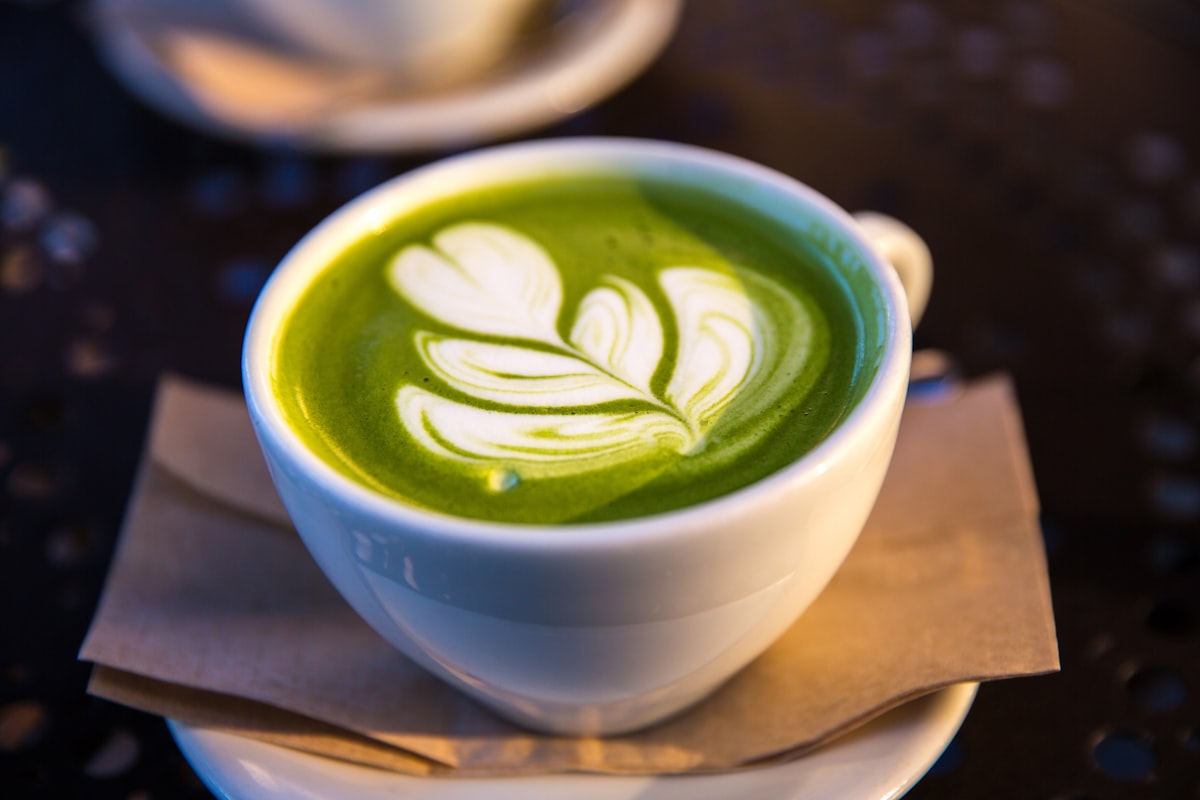 Creamy matcha latte with latte art in a white ceramic bowl